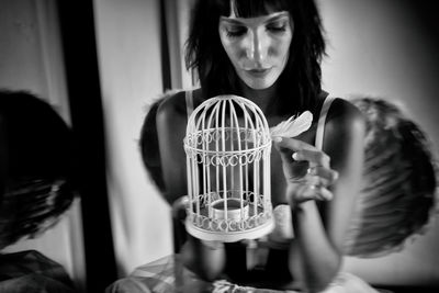 Woman holding feather by bird cage