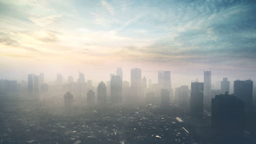 Modern buildings in city against sky during sunset