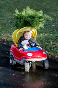 Toddler in toy car with christmas tree on the roof