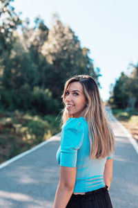 Portrait of smiling young woman standing on road