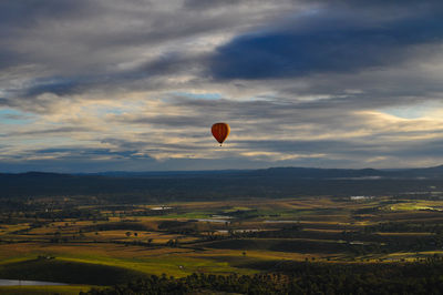 Hot air balloon flying over field against sky