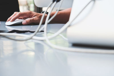 Cropped hand of man using computer on desk in office