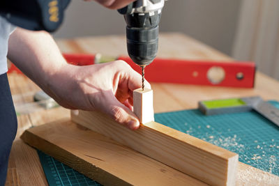 Drilling a hole in a tree with a metal drill on wood, the theme of craft and woodworking