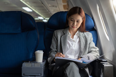 Businesswoman reading documents sitting in airplane