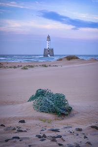 Lighthouse by sea against sky
