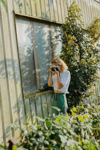 Woman photographing while standing by plants