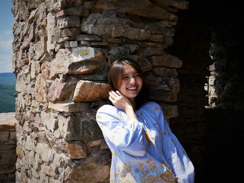 Portrait of smiling young woman standing against wall