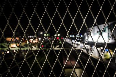 View of street seen through chainlink fence at night