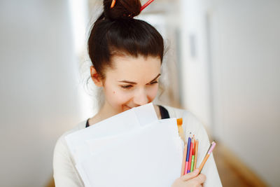 Close-up of woman holding papers and colored pencils