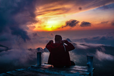 Rear view of man photographing against sky during sunset