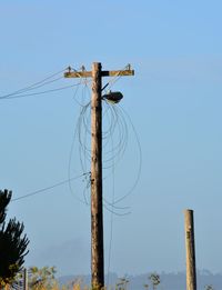 Low angle view of electricity pylon against clear blue sky