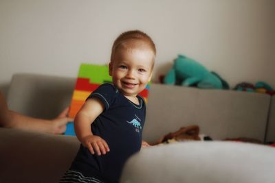 Portrait of smiling boy sitting on sofa at home