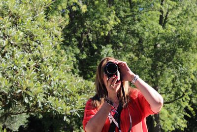 Woman photographing through digital camera during sunny day