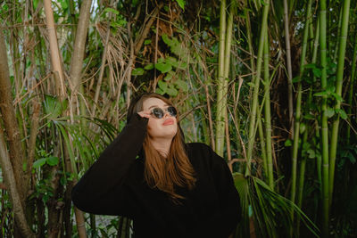 Portrait of young woman standing against plants