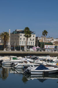 Boats moored at harbor against buildings in city