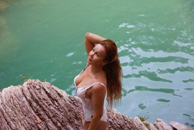 High angle view of woman wearing swimwear standing on rock over lake