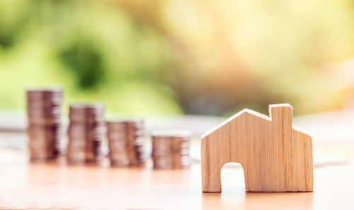 Close-up of wooden house with coins on table