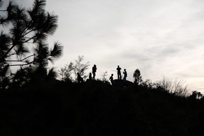 Low angle view of silhouette people by tree against sky