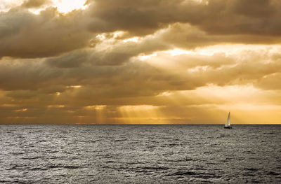 Scenic view of sea against cloudy sky during sunset