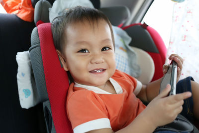 Portrait of cute boy using smart phone in car