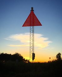 Low angle view of red tower on field against sky during sunset