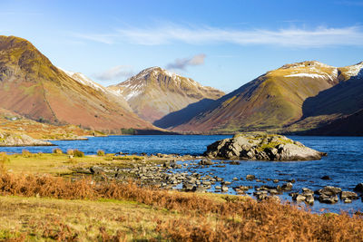 Scenic view of lake by mountains against sky