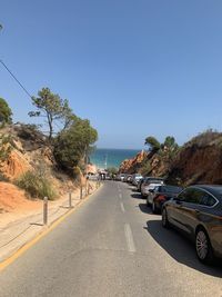 Road by sea against clear blue sky