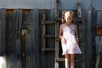 Portrait of cute girl standing against old house