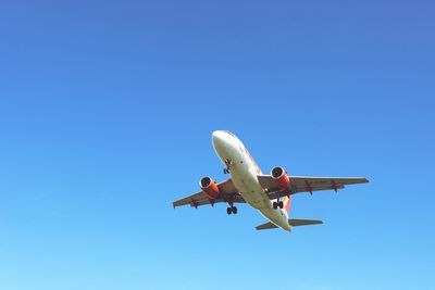 Low angle view of airplane against clear blue sky