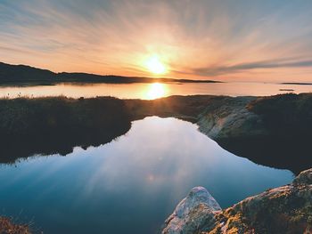 Sunset or sunrise with rich reflection in water pool. un is hanging at horizon close to sea or ocean