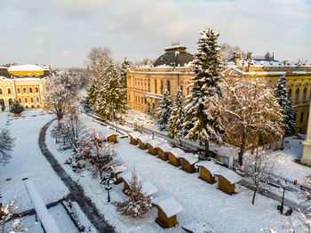 Snow covered street by buildings against sky