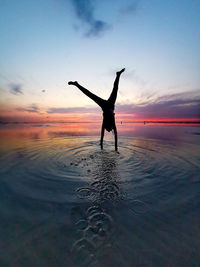 Handstand of a girl at sunset in the sea