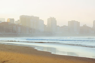 Sea by buildings against sky in city