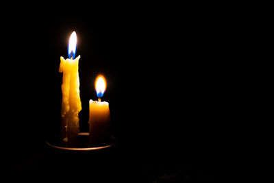 Close-up of illuminated candles against black background