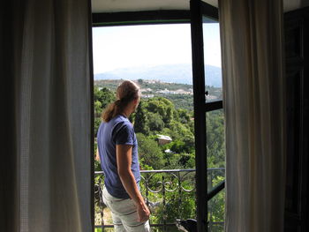 Woman looking through window at balcony