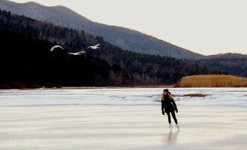 Man walking on snow covered mountain against clear sky