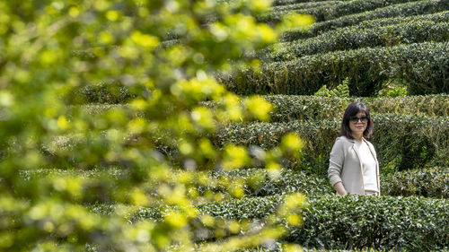 Portrait of woman standing by plants