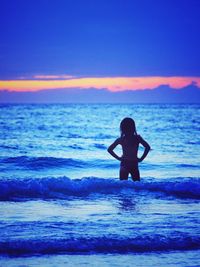 Silhouette man in sea against sky during sunset