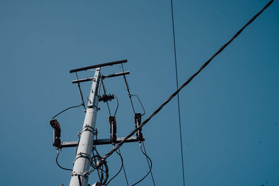 Low angle view of electricity pylon against clear sky