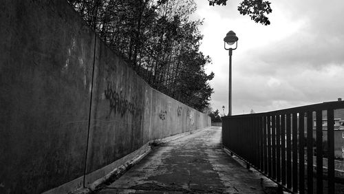 Walkway amidst street light against sky