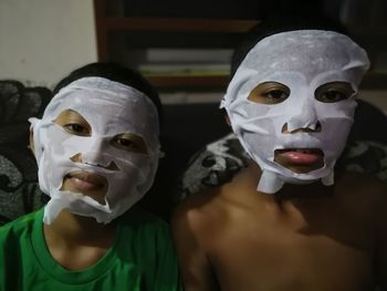 Close-up portrait of siblings wearing facial masks at home