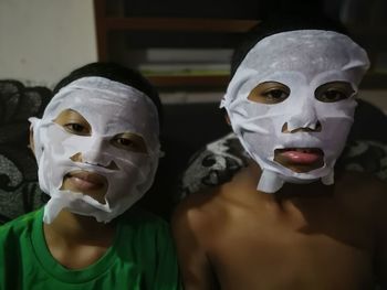 Close-up portrait of siblings wearing facial masks at home