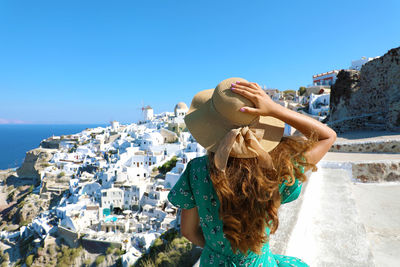 Rear view of woman standing against buildings at oia in santorini