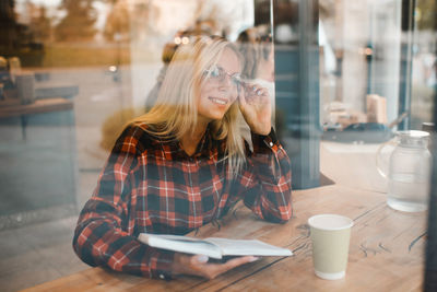 Young woman using mobile phone while sitting in cafe