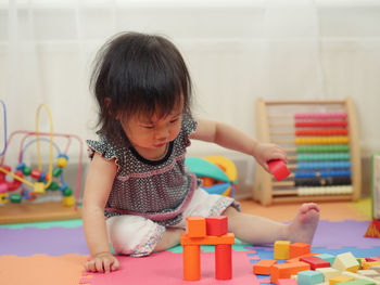 Girl playing with colorful toy blocks at home