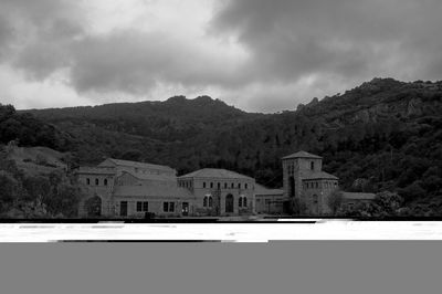 Buildings by mountains against sky