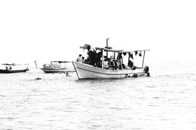 Boats in sea against clear sky