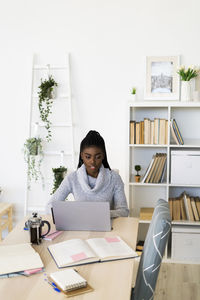 Female student concentrating while studying on laptop sitting at home