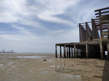 Wooden posts on beach against sky