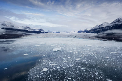 Scenic view of landscape against cloudy sky during winter